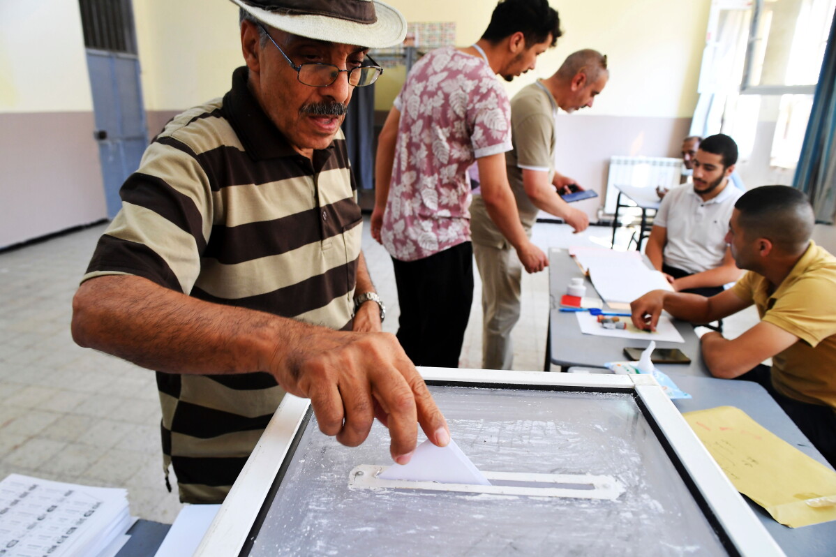 A voter places his ballot in a transparent box at a polling station in Algiers during Algeria's July 2, 2026, parliamentary election.