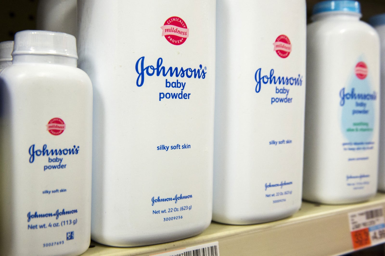 White bottles of Johnson's Baby Powder lined up on a store shelf.
