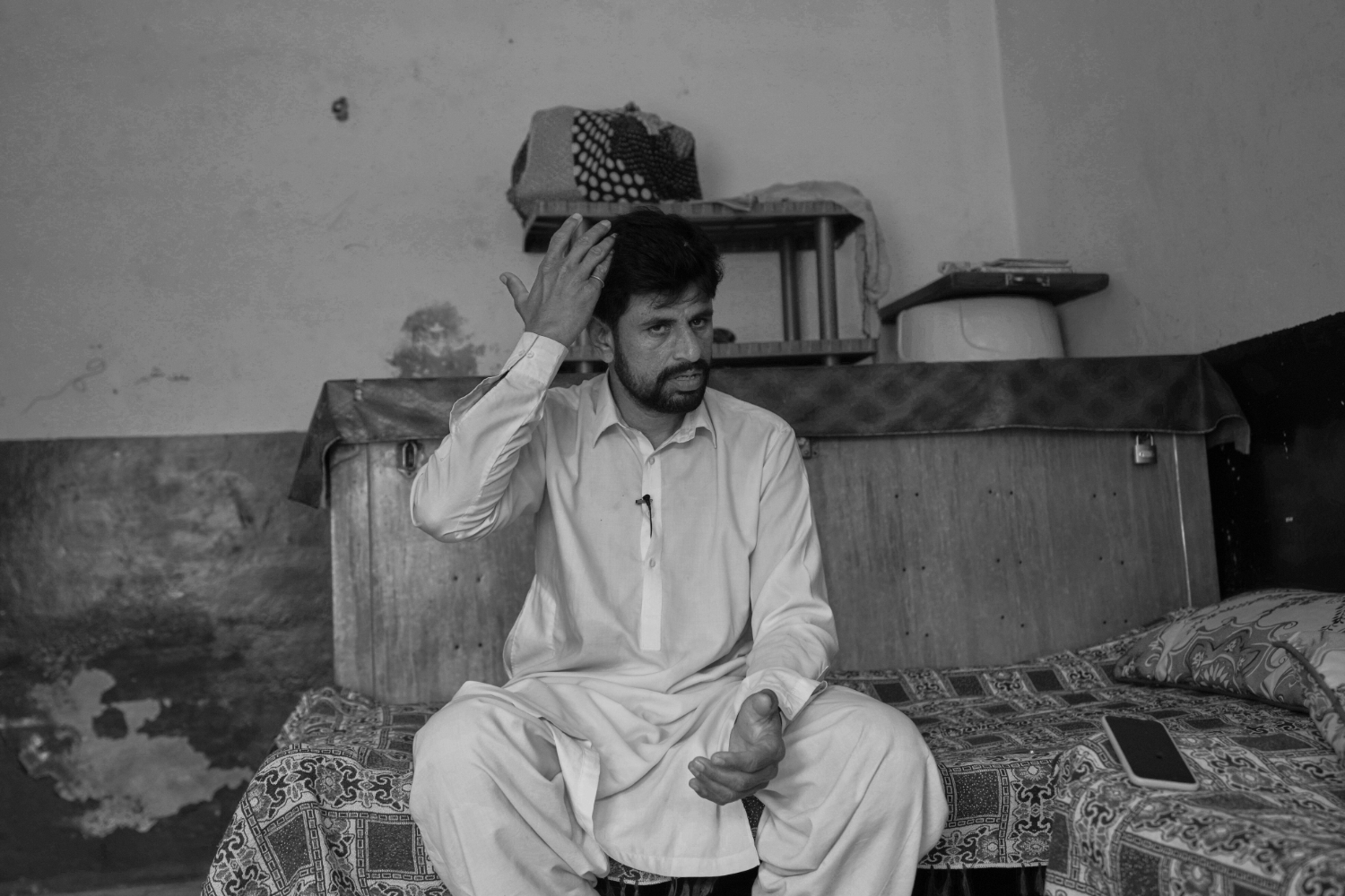 Atlantic-route survivor Imran Iqbal sits on a bed while recounting his failed 2025 boat journey from Mauritania toward Spain.