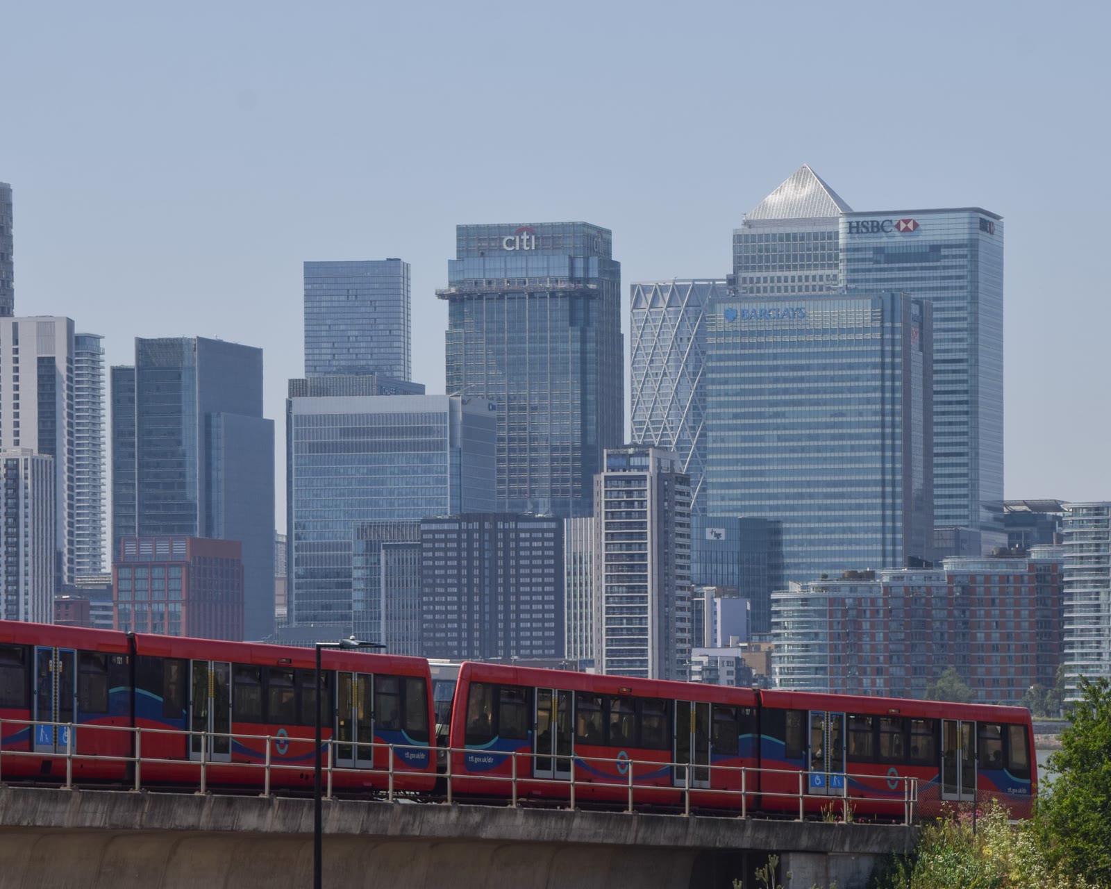 A red Docklands Light Railway train passes the office towers of Canary Wharf in London.