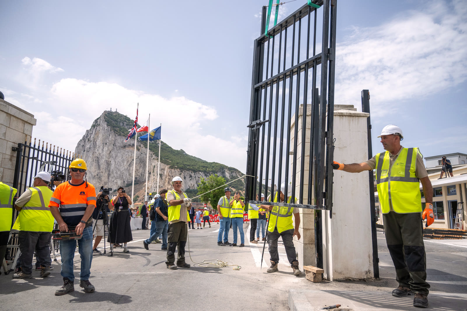 Workers in high-visibility clothing remove the fence between Gibraltar and Spain as the Rock of Gibraltar rises behind them.