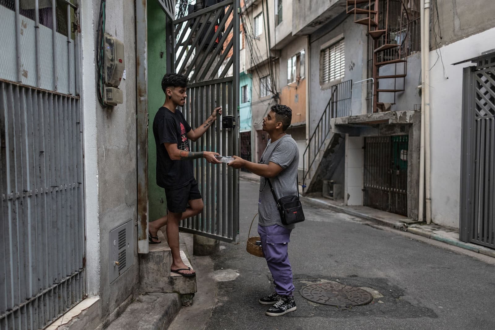 A volunteer hands an HIV and STI prevention kit to a resident in the Heliópolis community of São Paulo.