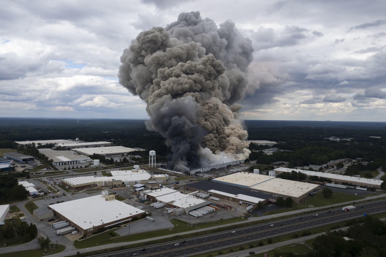A huge gray and black smoke plume rises from the burning BioLab facility beside Interstate 20 in Conyers, Georgia.