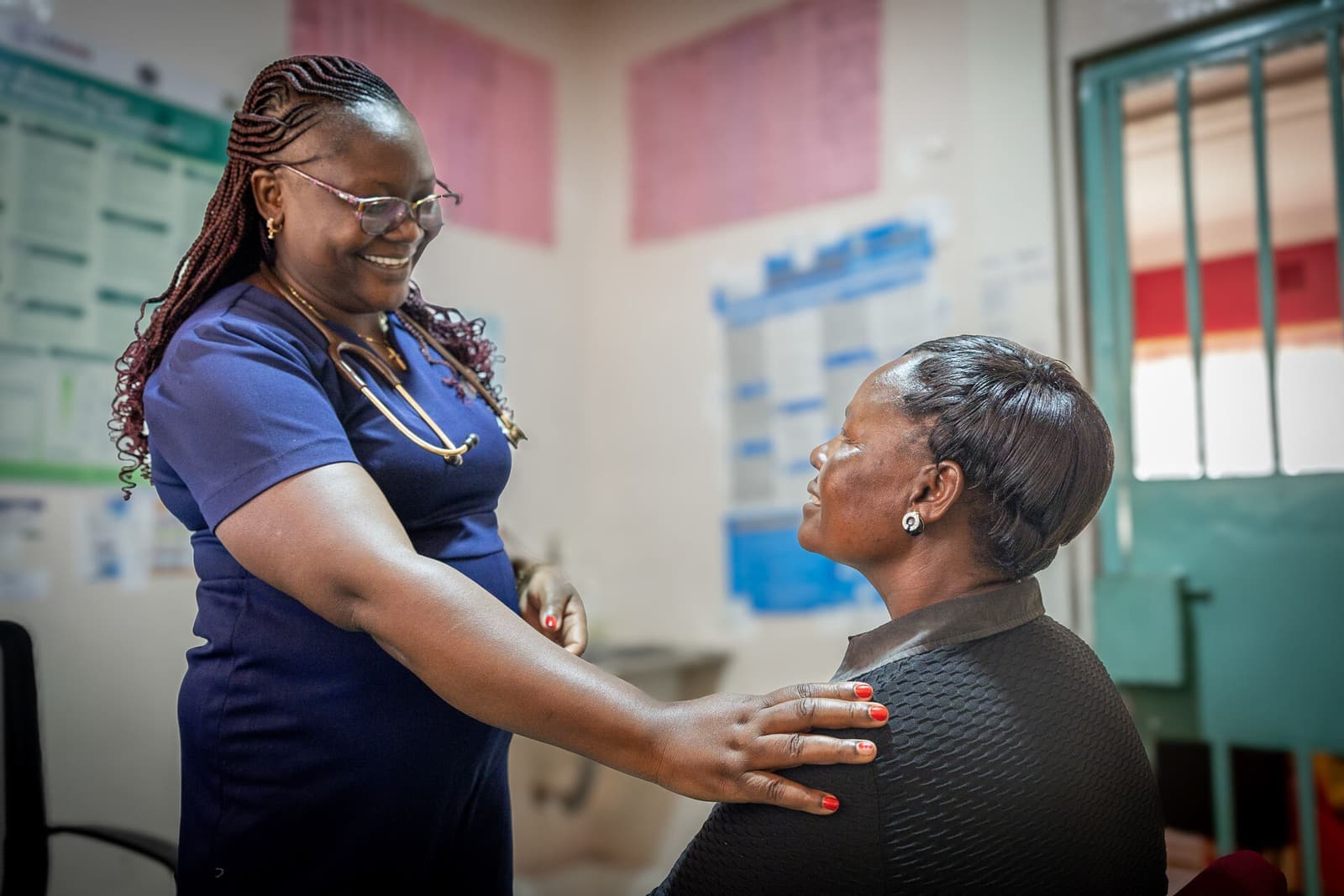 A health worker in Kenya comforts a seated patient during an integrated cancer screening visit.