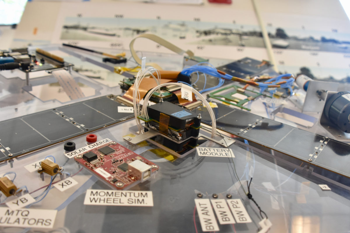 The LightSail BenchSat engineering model lies on a clear acrylic board, surrounded by labeled solar-charging, battery, momentum-wheel, and antenna components.