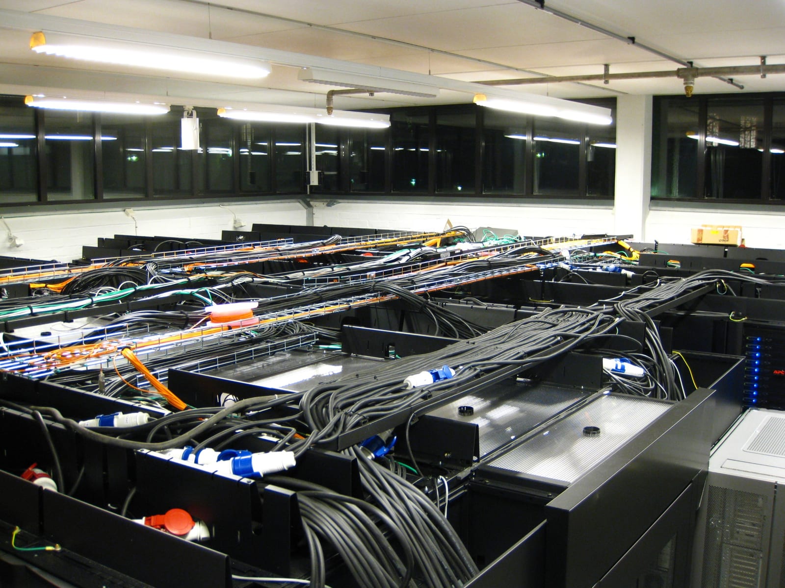 Rows of black server cabinets crossed by dense power, fiber-optic, and Ethernet cabling in the Parallel Computer Center at Sweden's Royal Institute of Technology.