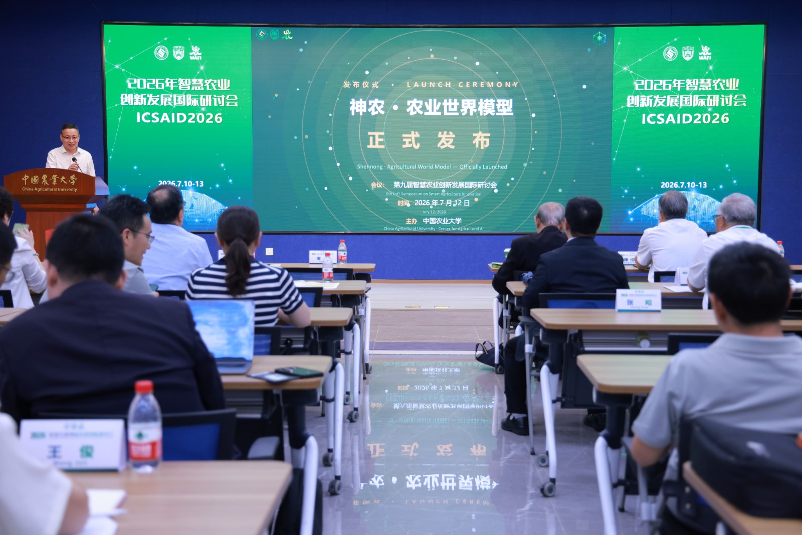 观众在中国农业大学观看神农·农业世界模型发布会，台上讲者站在一块绿色大屏旁。