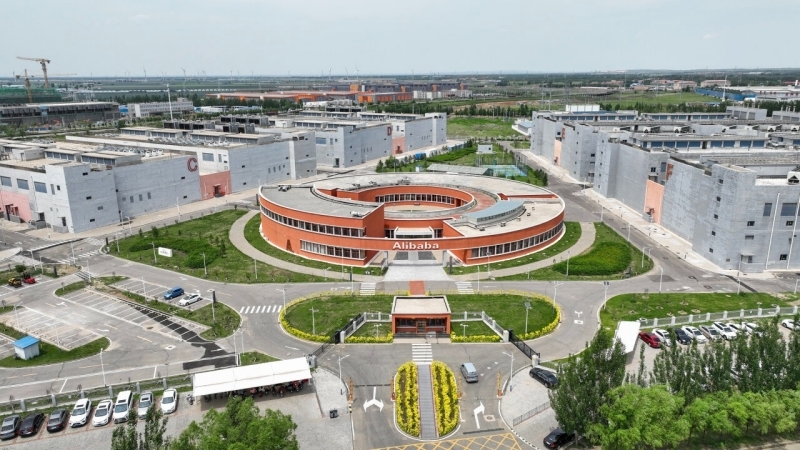 阿里云张北数据中心园区航拍图：一座红砖圆形建筑坐落在多排狭长的服务器机房之间。