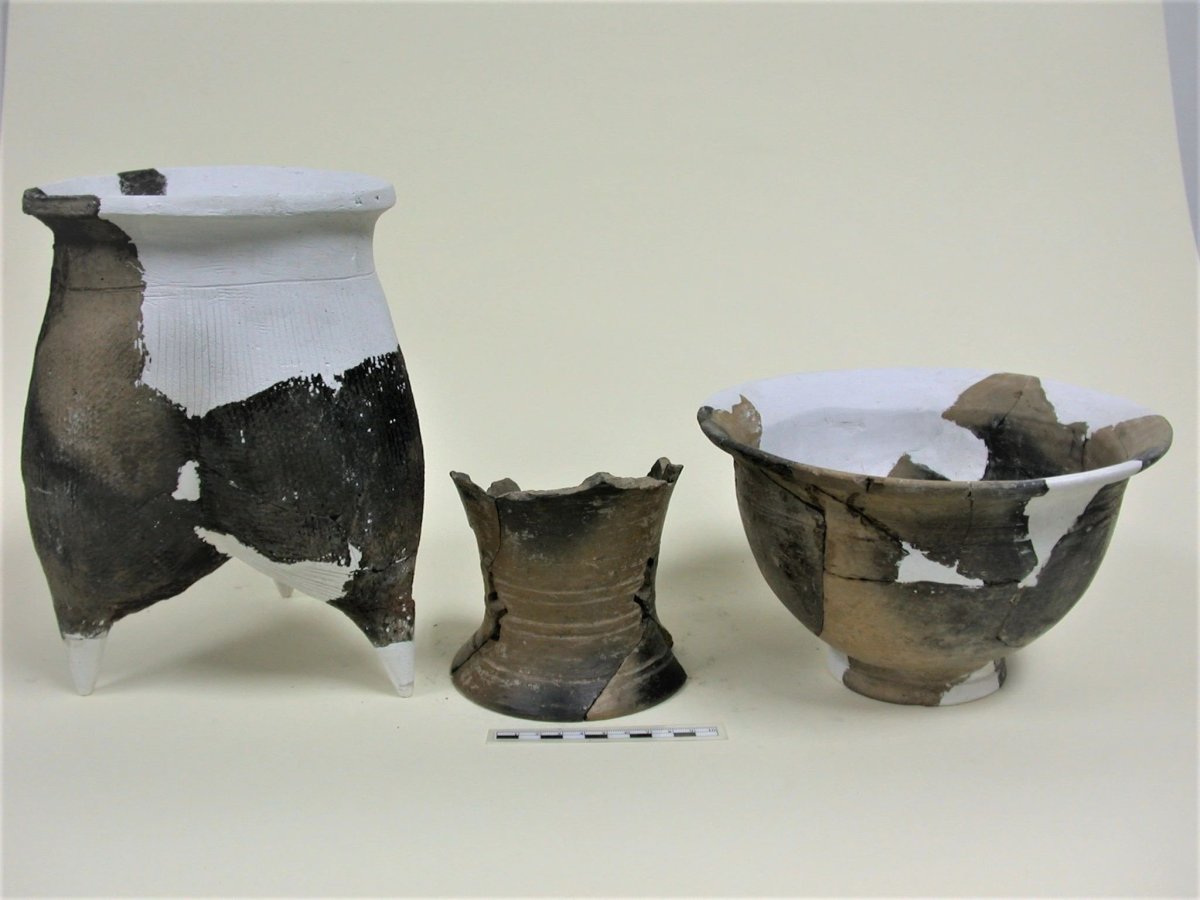 Three partially reassembled gray pottery vessels from the Daxinzhuang archaeological site, with missing areas filled in white.
