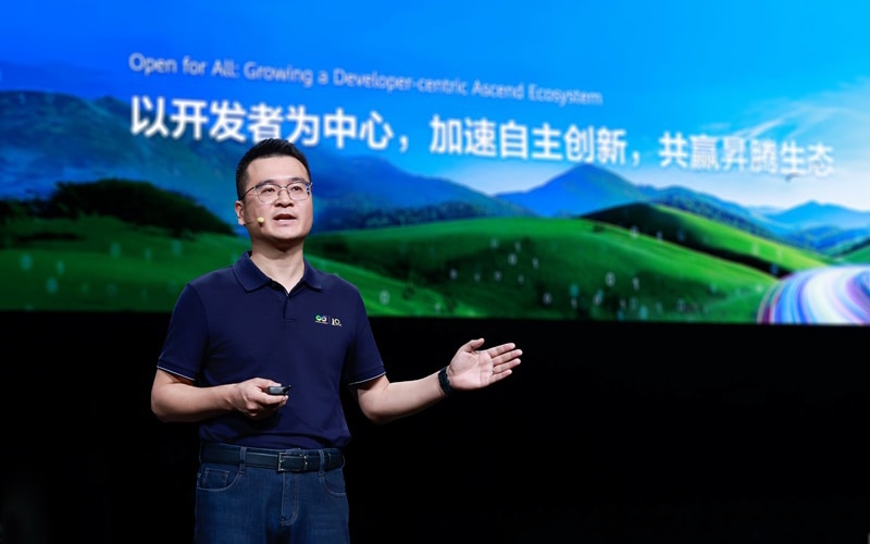 张迪煊在舞台上演讲，身后屏幕正在介绍开放、以开发者为中心的昇腾生态。