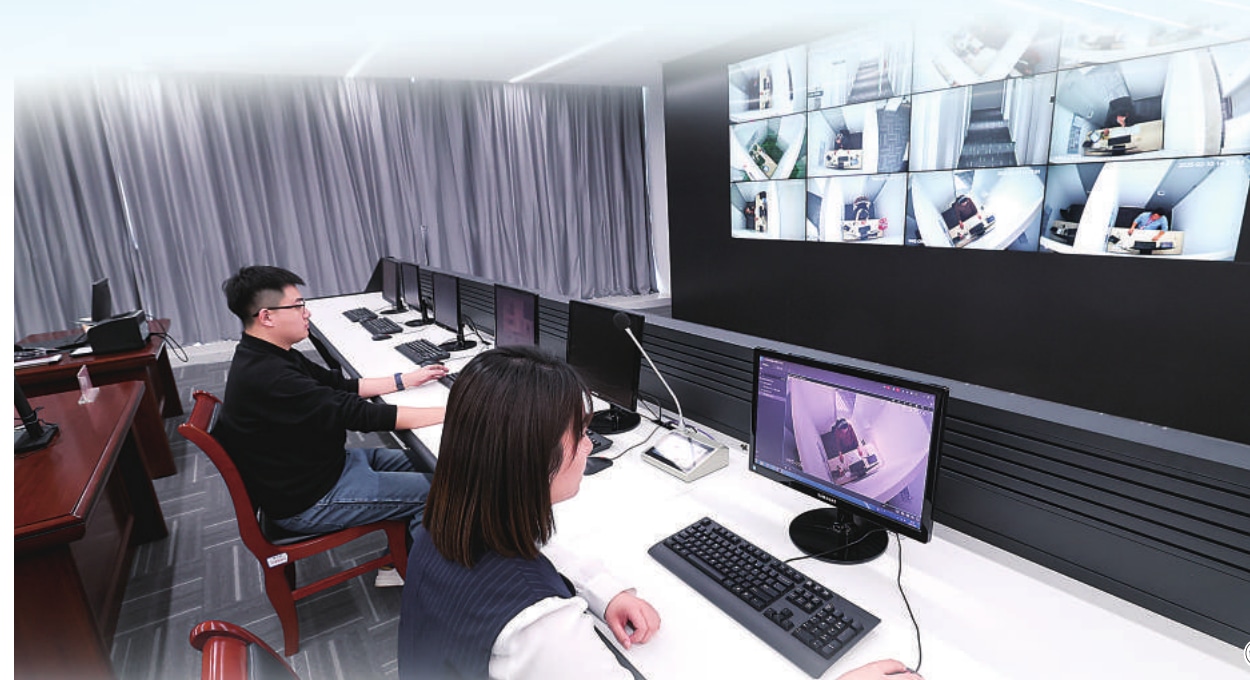 Staff at the Shijiazhuang Public Resources Trading Center monitor evaluation rooms on a wall of live video screens.