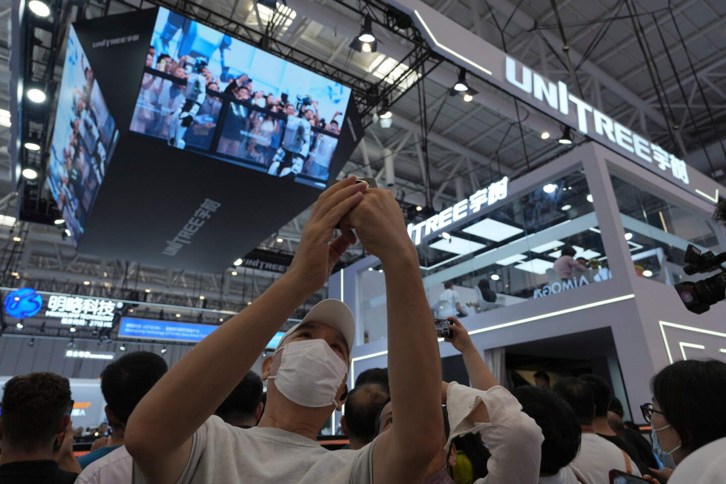 2026 年 8 月，参观者在北京世界机器人大会巨大的 Unitree 字样旁留影。