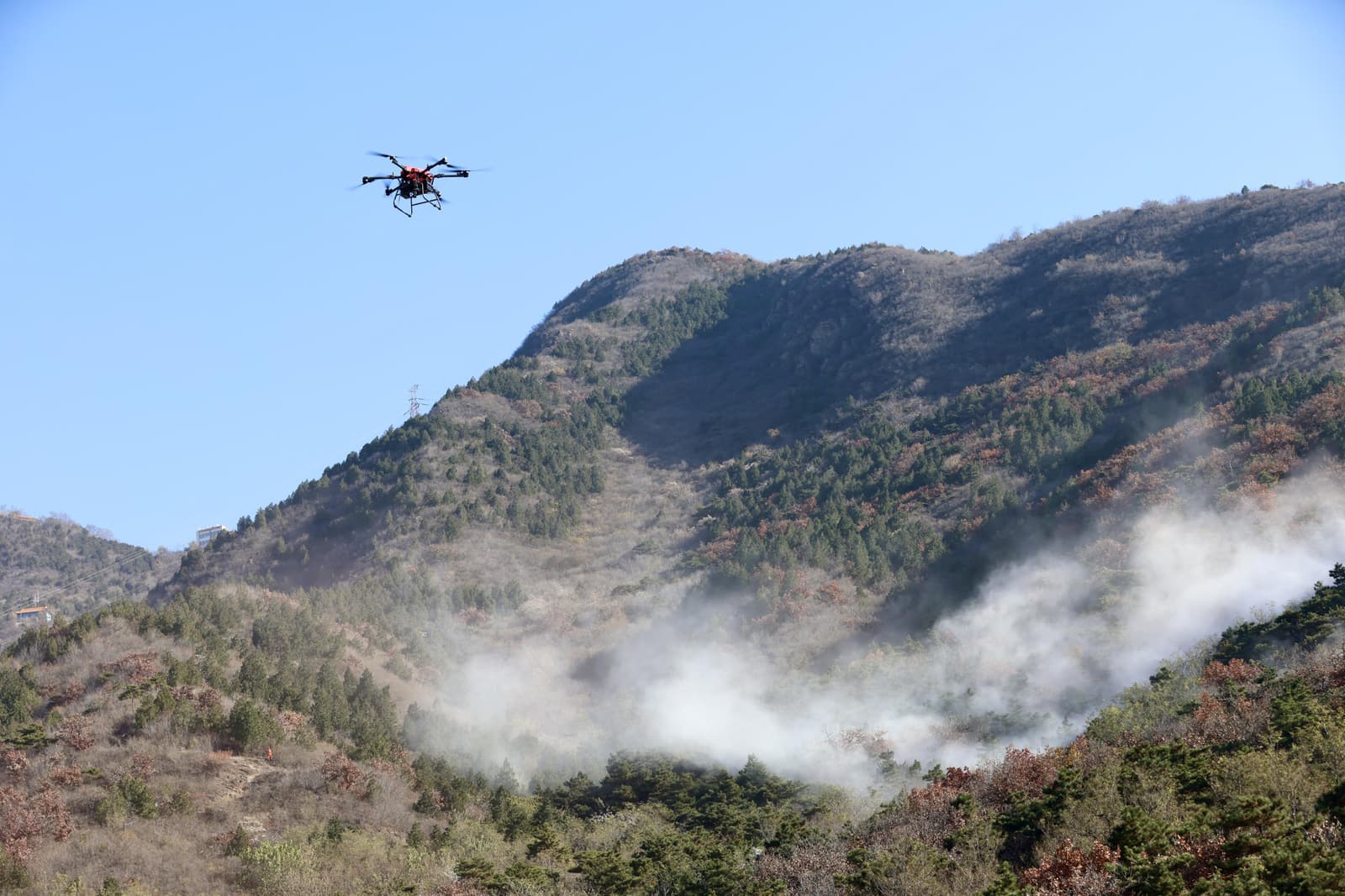 A quadcopter patrols above a wooded slope during a forest-fire exercise at Beijing's Ming Tombs Forest Farm.
