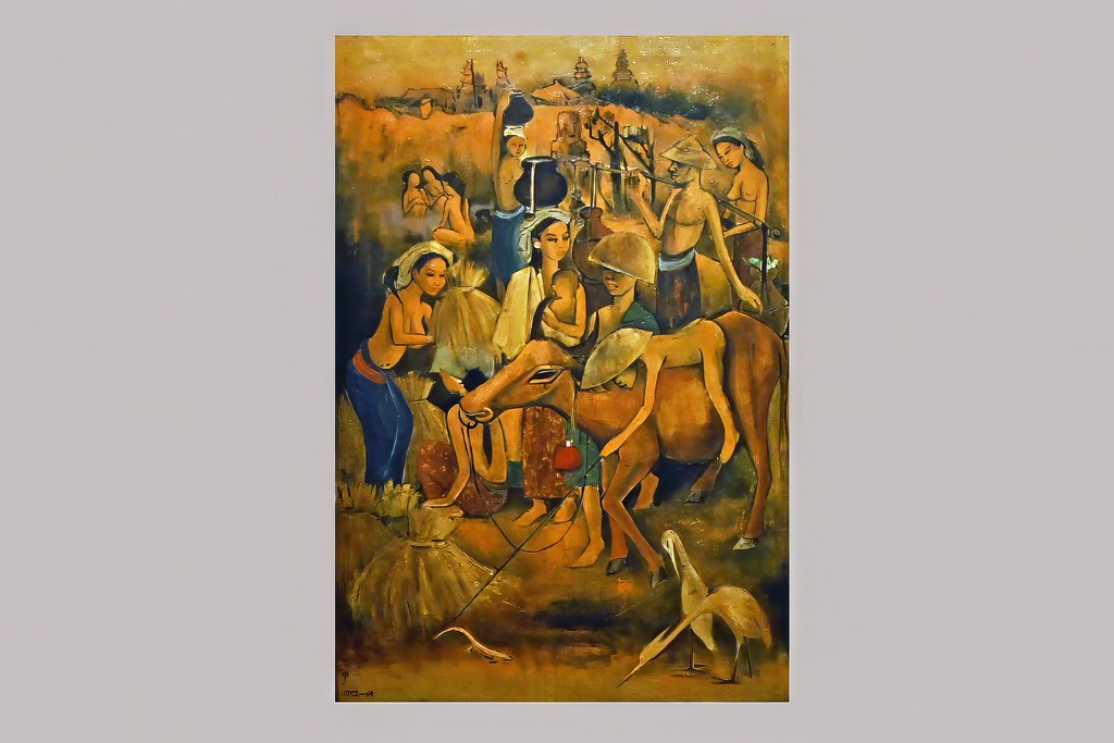 钟泗滨的高幅画作《巴厘村庄》摄于浅色展墙前，成群人物、牲畜、房屋与树木铺陈在琥珀色、赭色、蓝色和绿色之间。