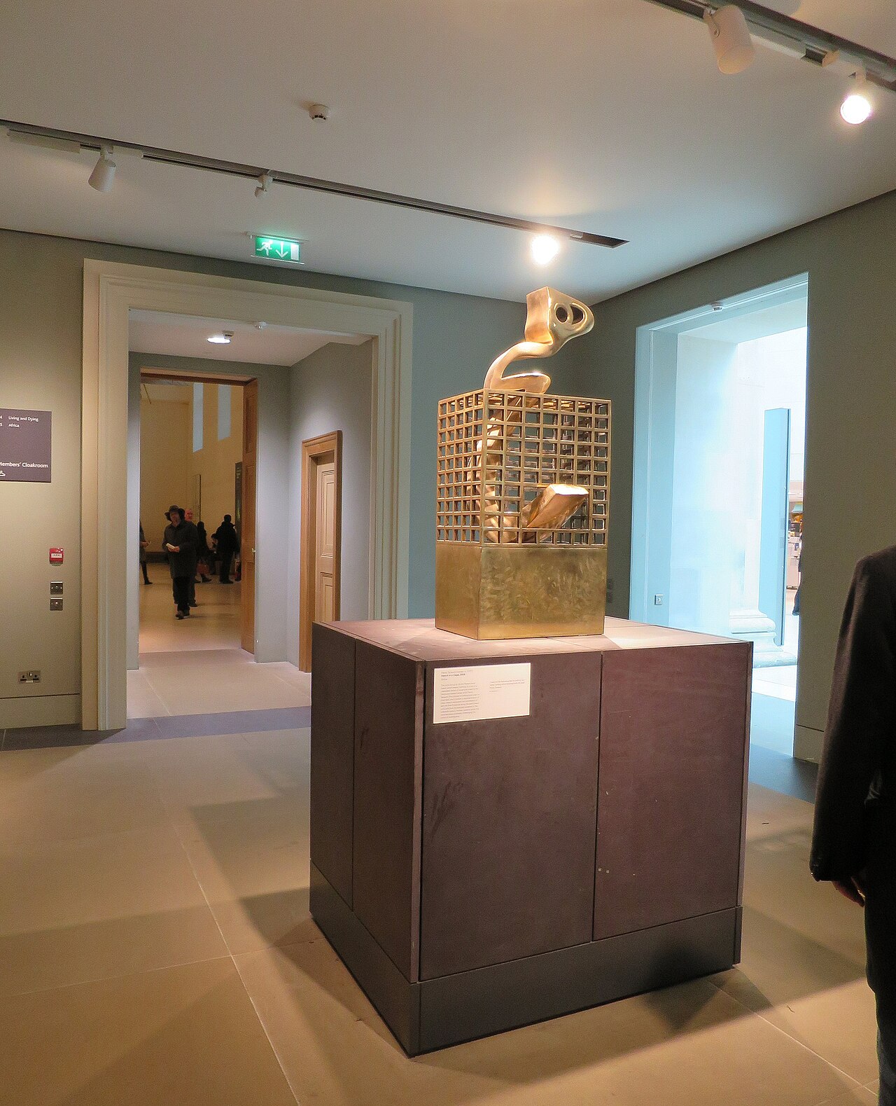 大英博物馆展厅内，帕尔维兹·塔纳沃利的青铜雕塑 Heech in a Cage：盘曲的波斯文字形体困在一座高耸的长方形格栅中。