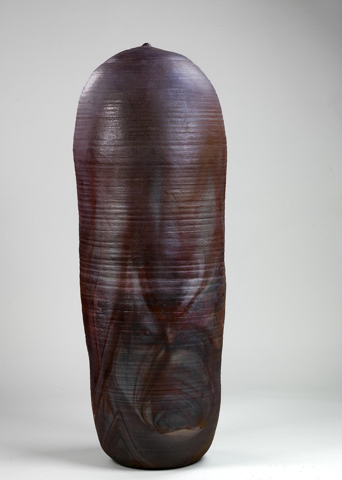 Museum photograph of Toshiko Takaezu's tall closed stoneware form Anagama, its aubergine and red-brown glaze flowing around a narrow body and domed top with a tiny vent.