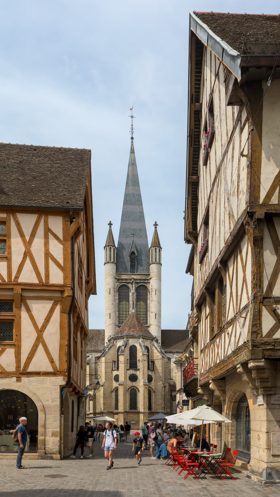 Rue de la Chouette in Dijon, with pedestrians between half-timbered buildings and the apse and spire of Notre-Dame ahead.