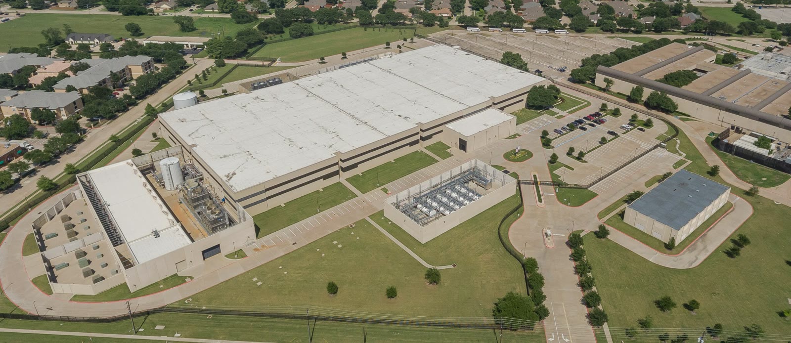 Aerial view of CoreWeave's Plano, Texas, data center, including the main building, cooling plant, electrical yard, and surrounding roads.