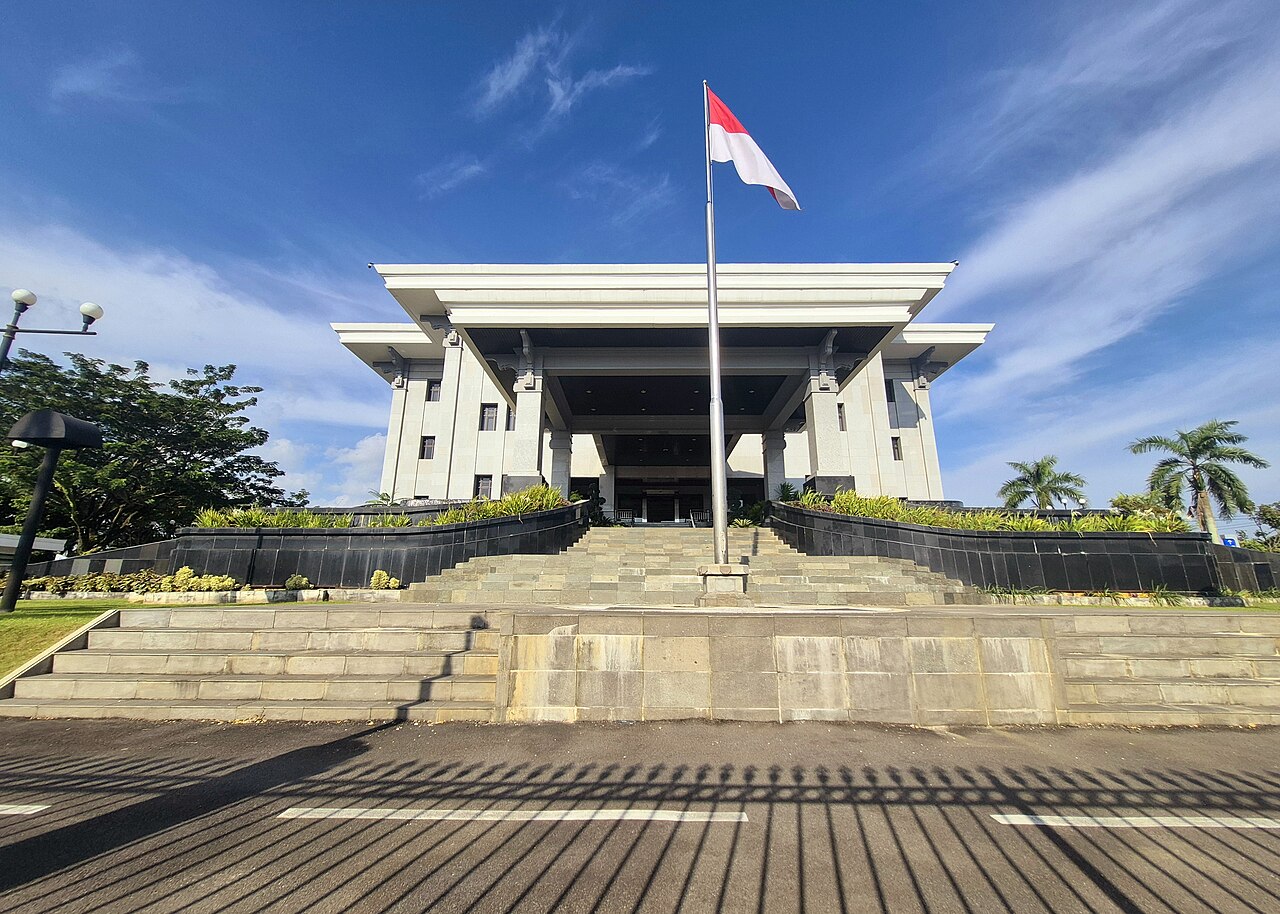 Bank Indonesia's West Kalimantan representative office in Pontianak beneath a blue sky, with the Indonesian flag flying above its broad front steps.