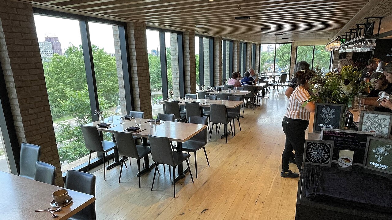 明尼阿波利斯原 Owamni 餐厅内景，食客坐在木条格栅天花板下。