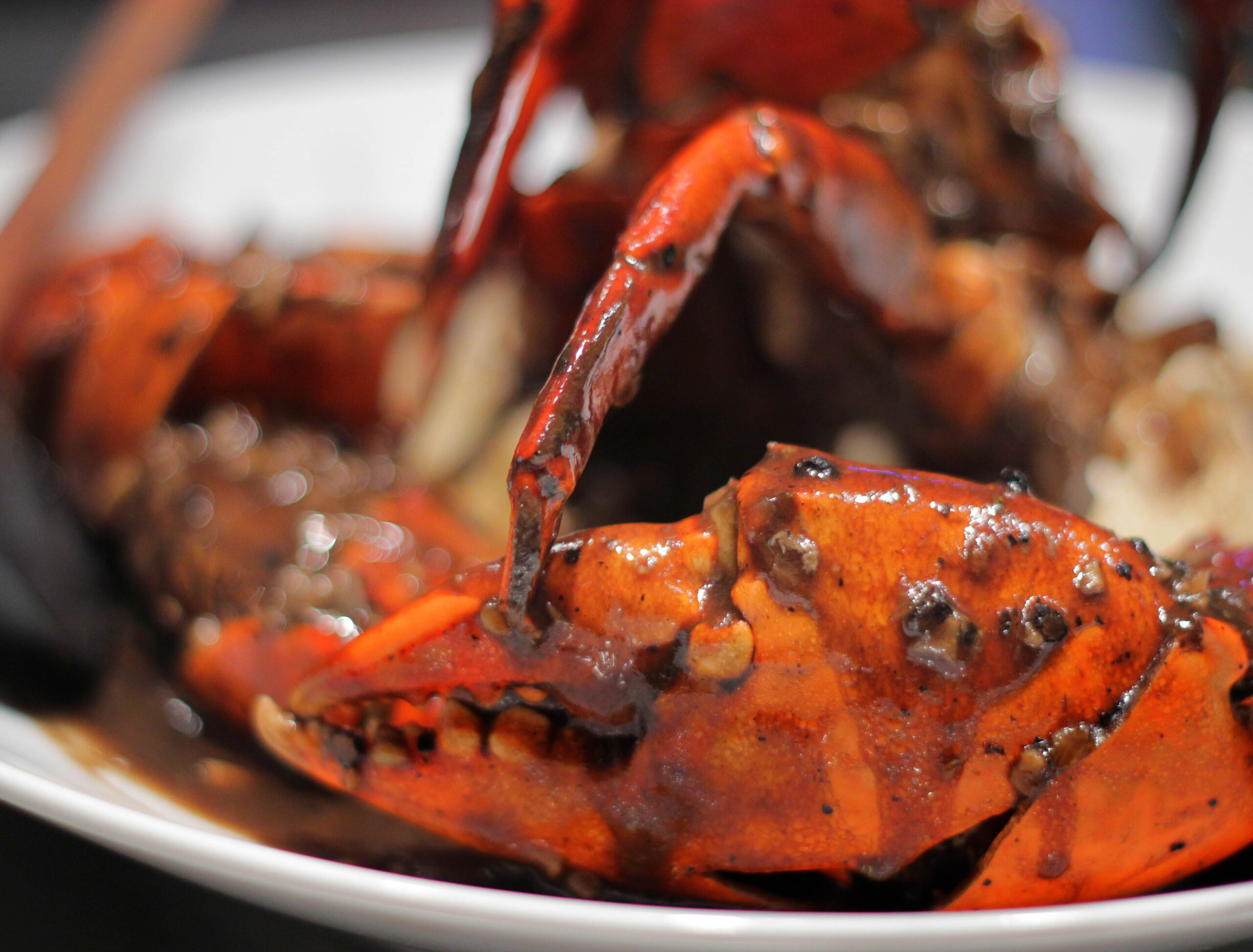 Ministry of Crab 胡椒蟹的近景照片：白碗里，红色蟹壳裹着油亮的深色胡椒酱。