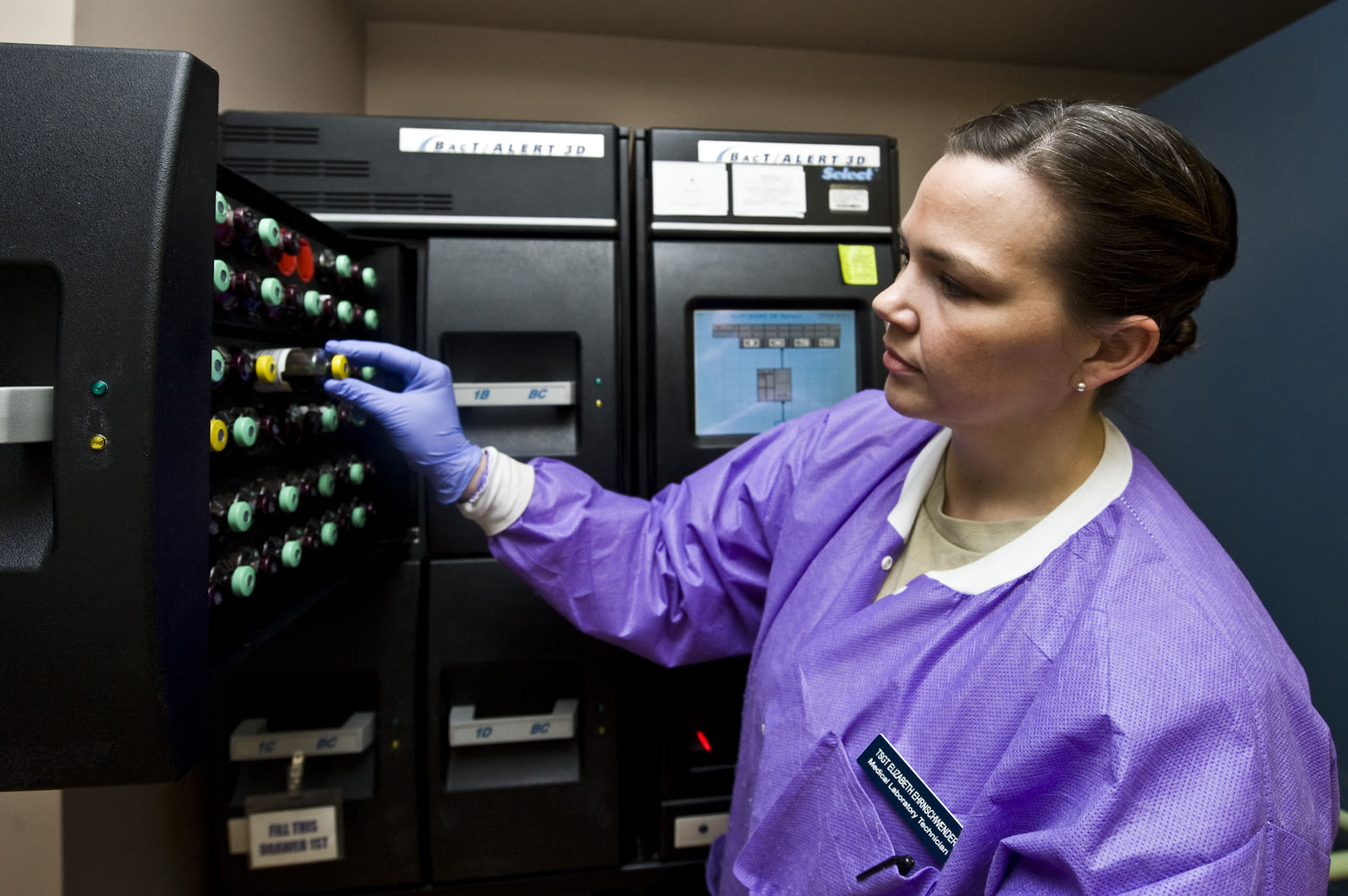 A clinical laboratory technologist unloads blood-culture bottles from a BacT/ALERT 3D instrument.