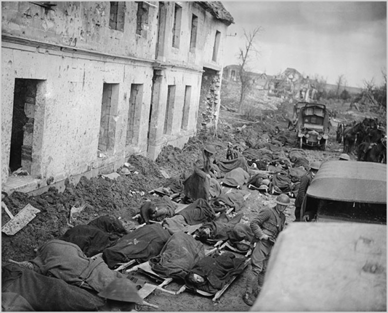 Wounded soldiers on stretchers outside a shell-damaged dressing station at Blangy, France, waiting for transport in April 1917.