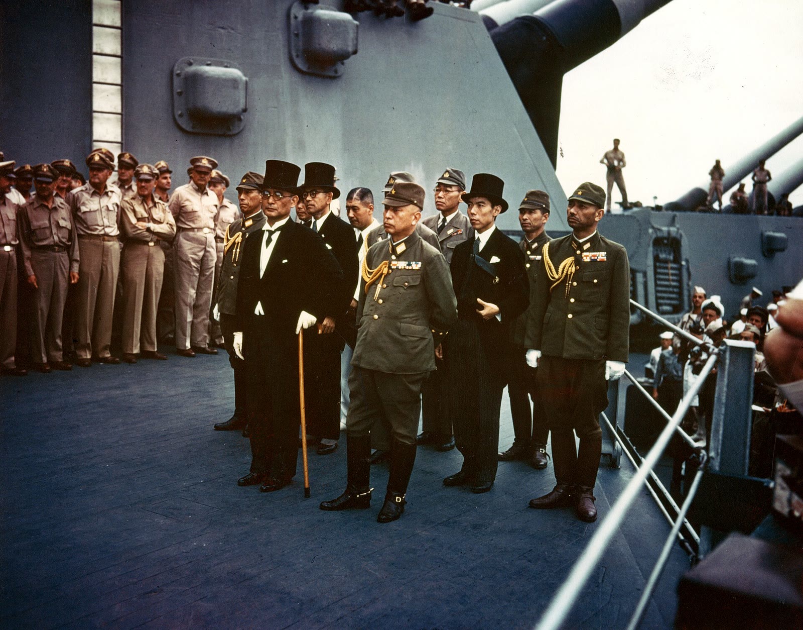 A color Army Signal Corps photograph shows Japan's surrender delegation standing aboard USS Missouri on 2 September 1945, with Foreign Minister Mamoru Shigemitsu in a top hat at front left and General Yoshijiro Umezu beside him.