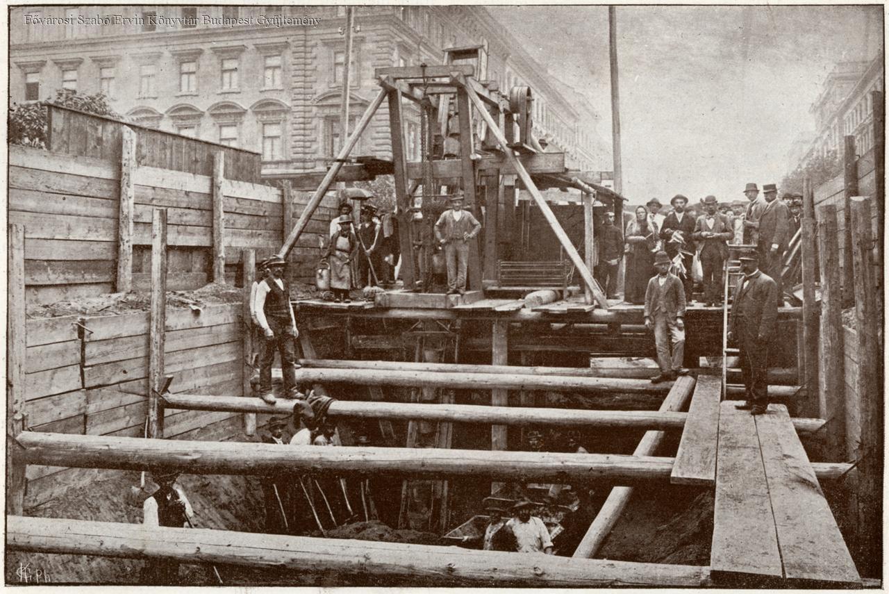 Black-and-white 1895 photograph of workers and an electric excavator inside the open cut for Budapest's Millennium Underground beneath Andrássy Avenue.