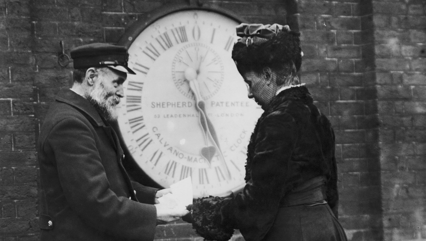Ruth Belville receives a timekeeping certificate from a Royal Observatory attendant in front of the Shepherd Gate clock.