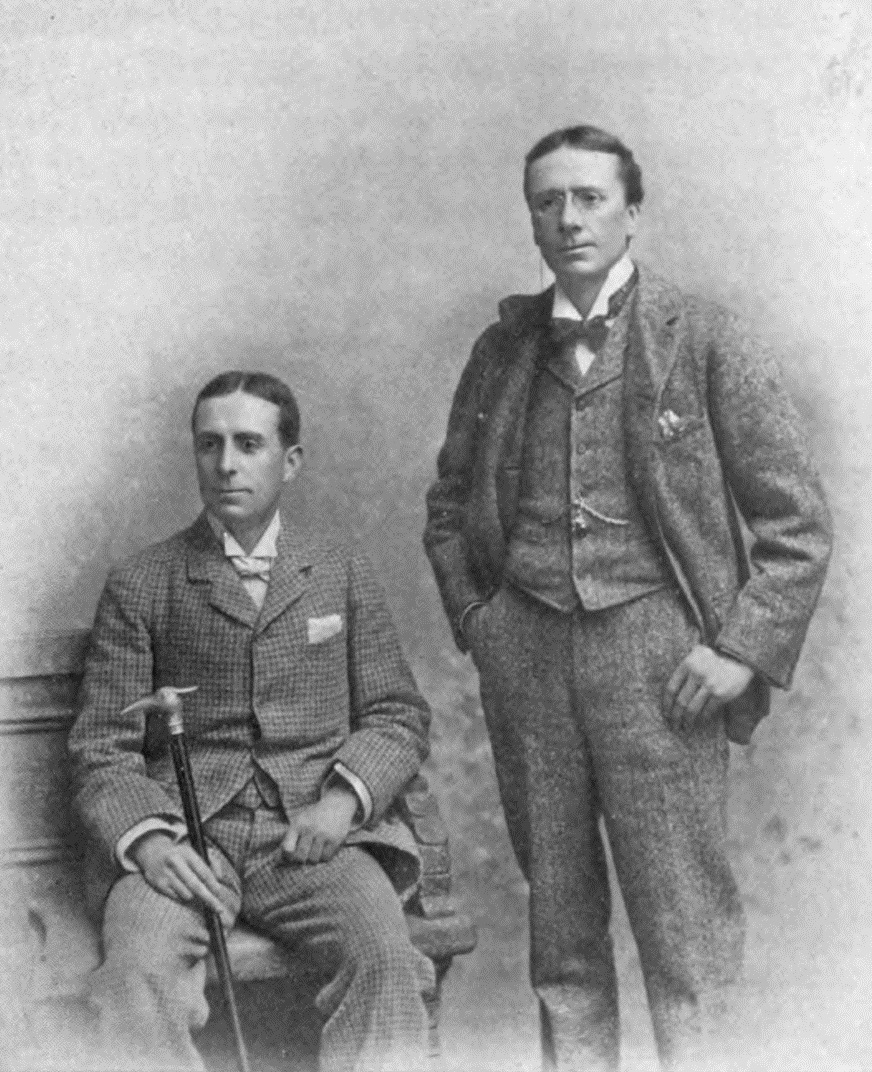 Black-and-white studio photograph of Weedon Grossmith seated with a cane at left and George Grossmith standing beside him at right.