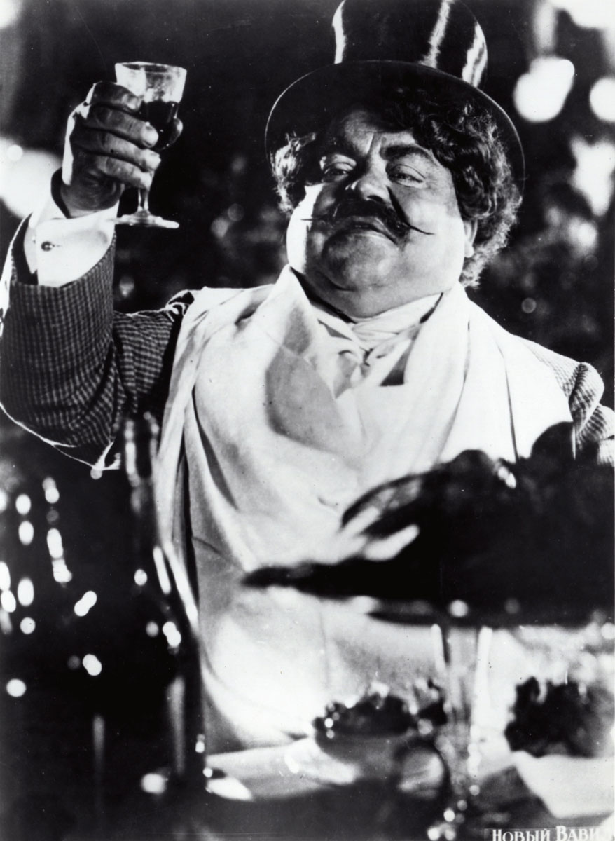 A top-hatted bourgeois reveler raises a stemmed glass in a high-contrast black-and-white still from The New Babylon.