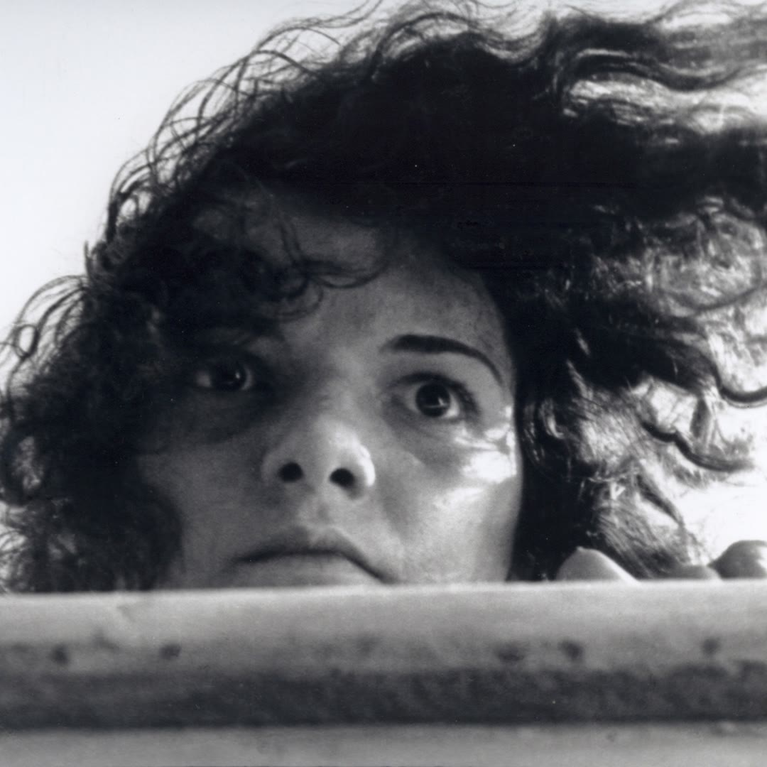A woman's windblown face rises above the edge of a rowboat in a black-and-white still from Limite.
