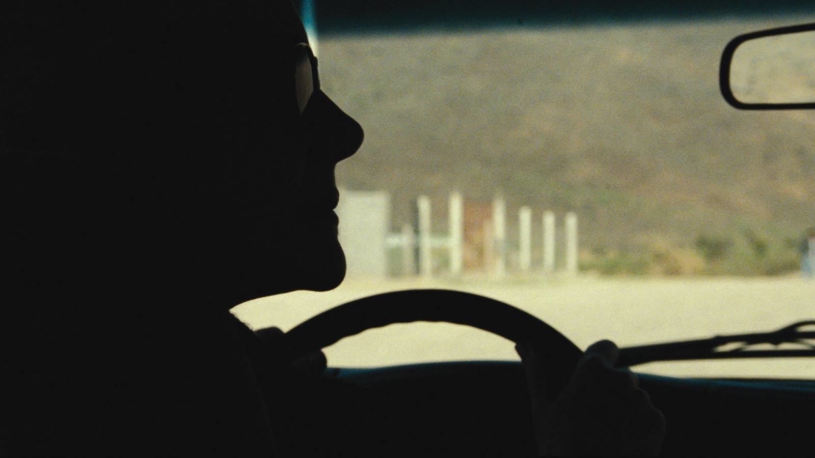 María Onetto as Verónica in dark profile at the wheel of a car, with a pale road visible through the windshield.
