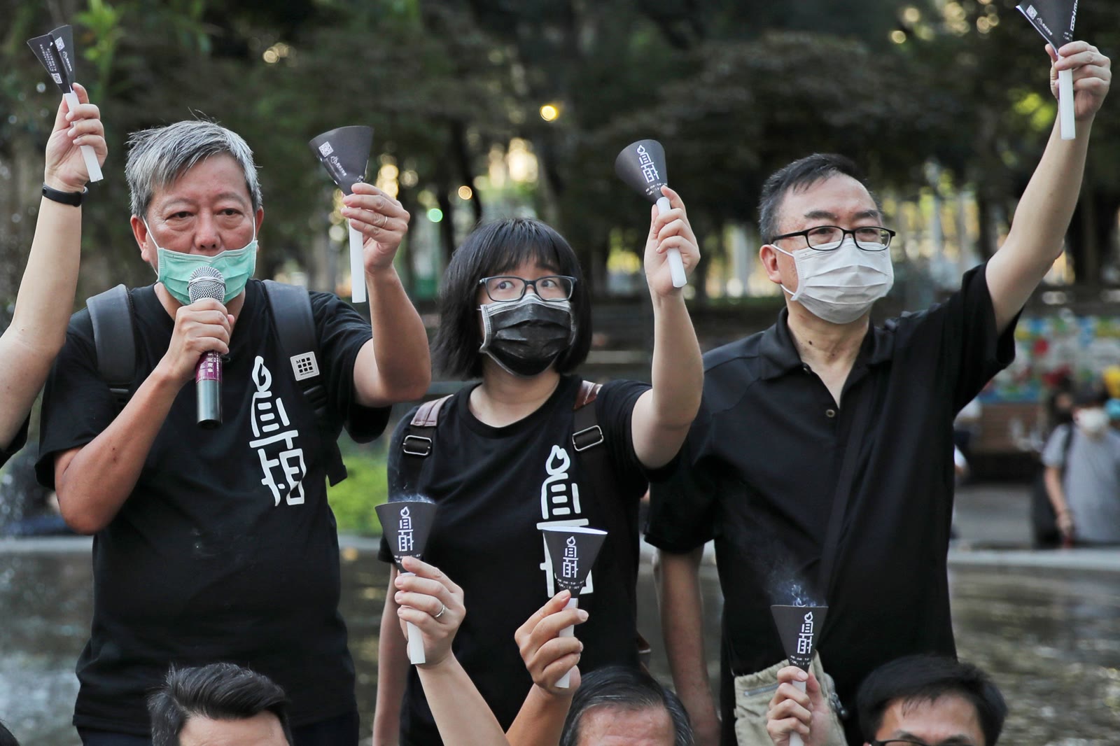 Lee Cheuk-yan, Chow Hang-tung and Cheung Man-kwong stand together holding candles at a Tiananmen remembrance gathering in Hong Kong's Victoria Park.