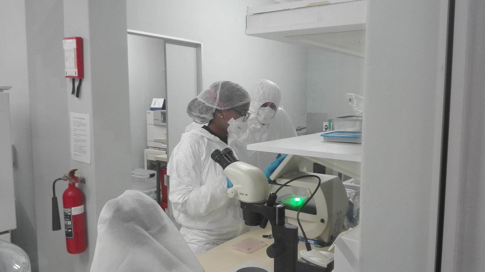 Two tuberculosis researchers in white protective coveralls and respirators work with laboratory equipment at the University of Cape Town.