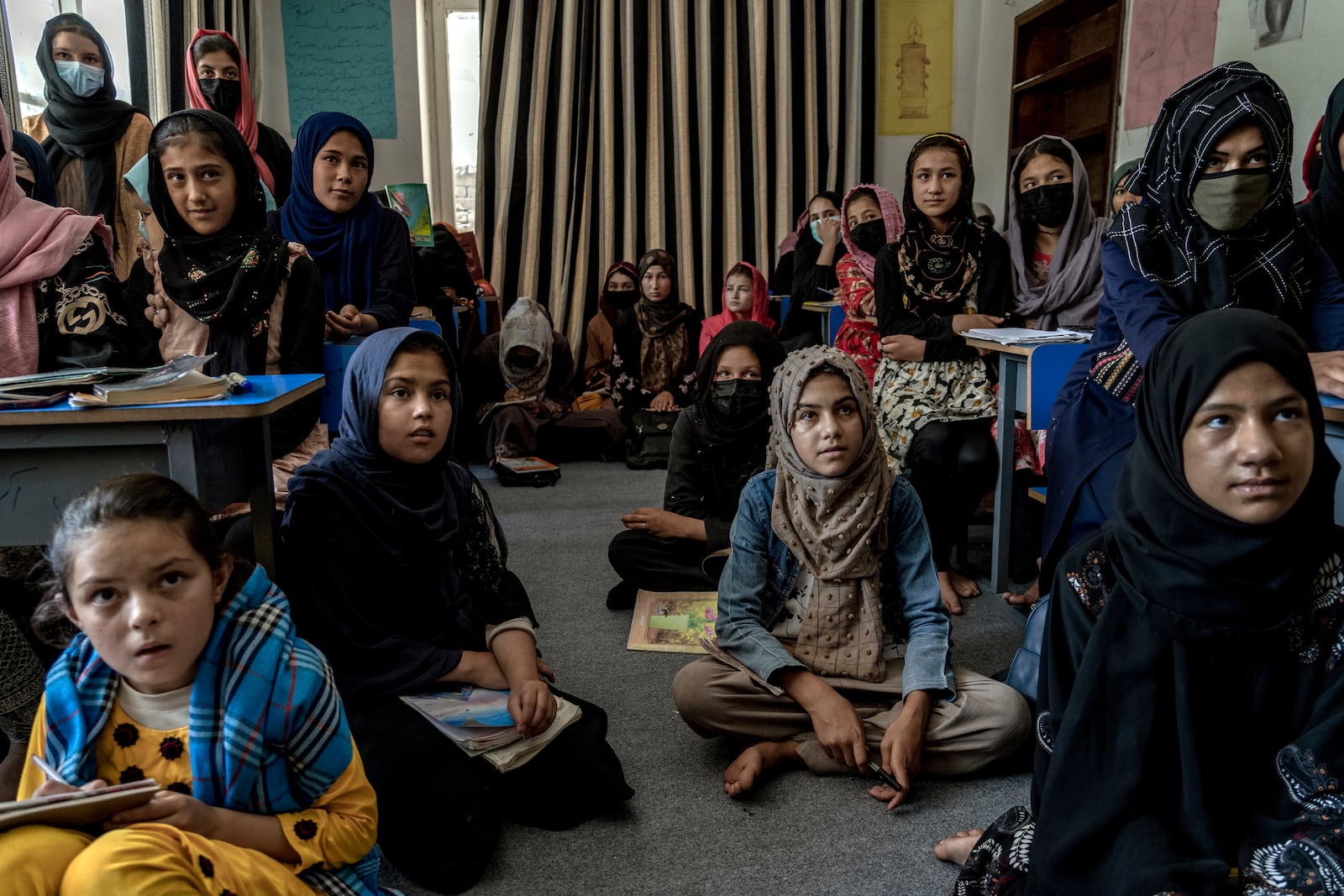 Afghan girls sit at desks and on the floor during an underground class in Kabul.