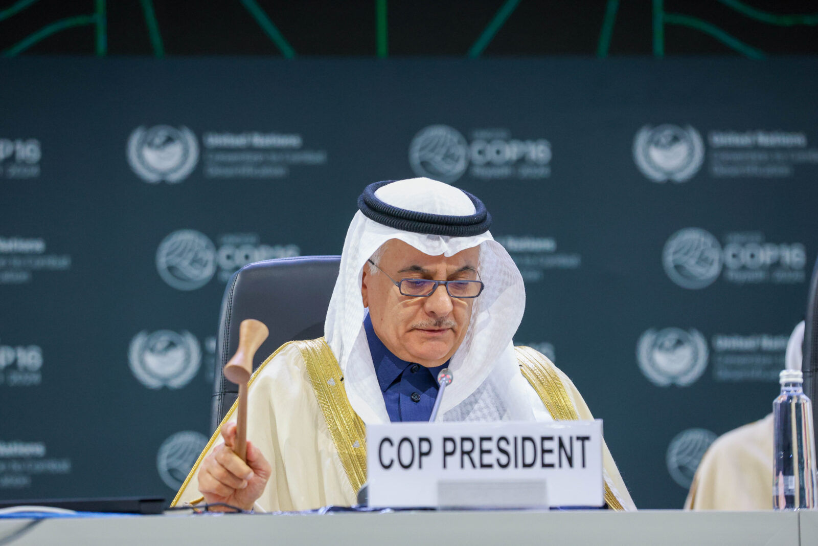 UNCCD COP16 President Abdulrahman AlFadley holds a wooden gavel behind a COP President nameplate at the closing plenary in Riyadh.