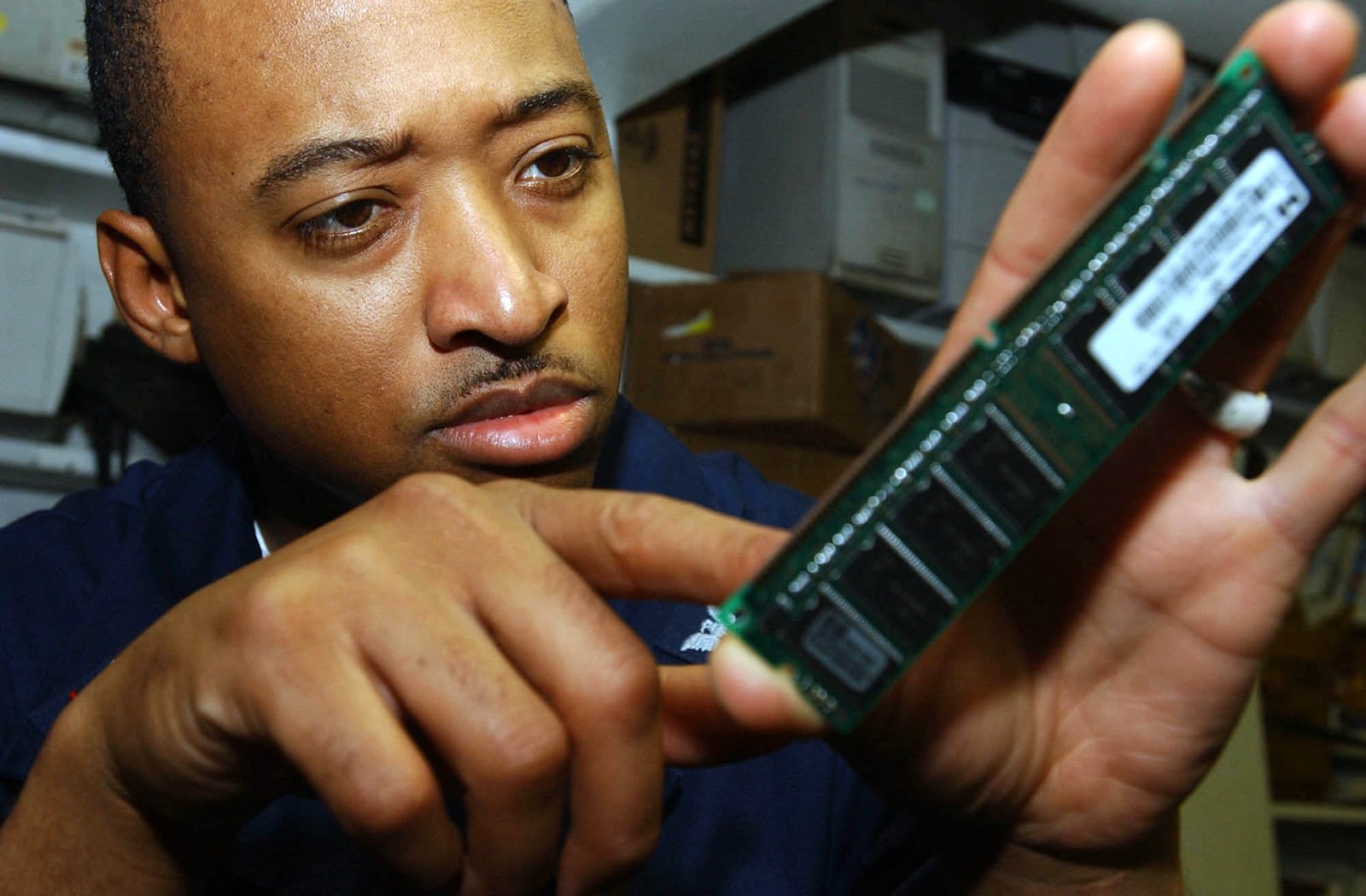 A U.S. Navy electronics technician closely inspects a RAM module aboard USS Nimitz.
