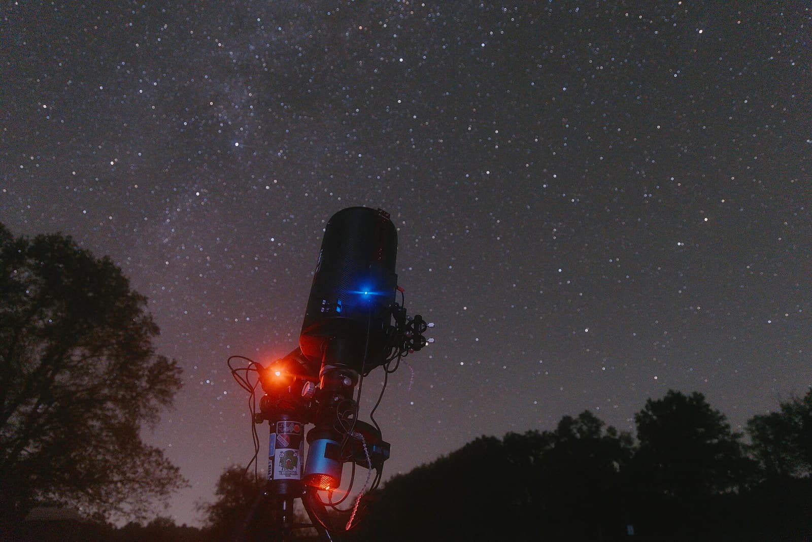 A Ritchey–Chrétien telescope and attached imaging equipment silhouetted beneath a star-filled sky at Kickapoo Valley Reserve.