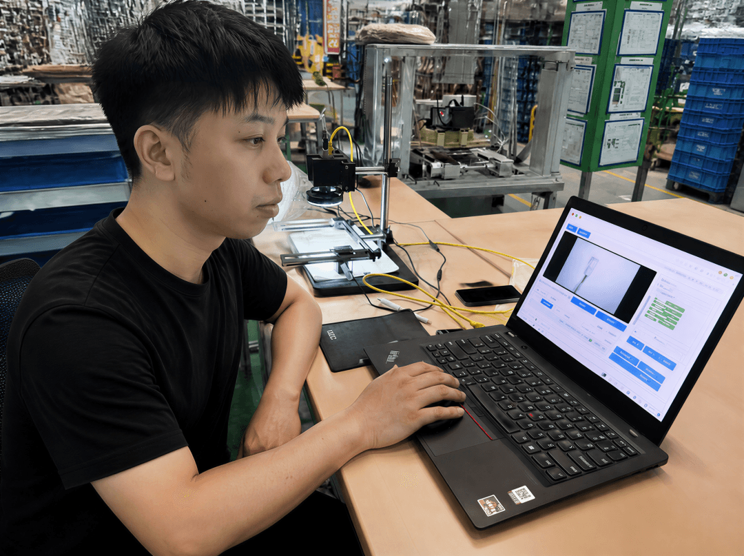 Sileco founder Yin Xing uses a laptop to debug an AI seat-cover inspection device beside an automotive supplier’s production line