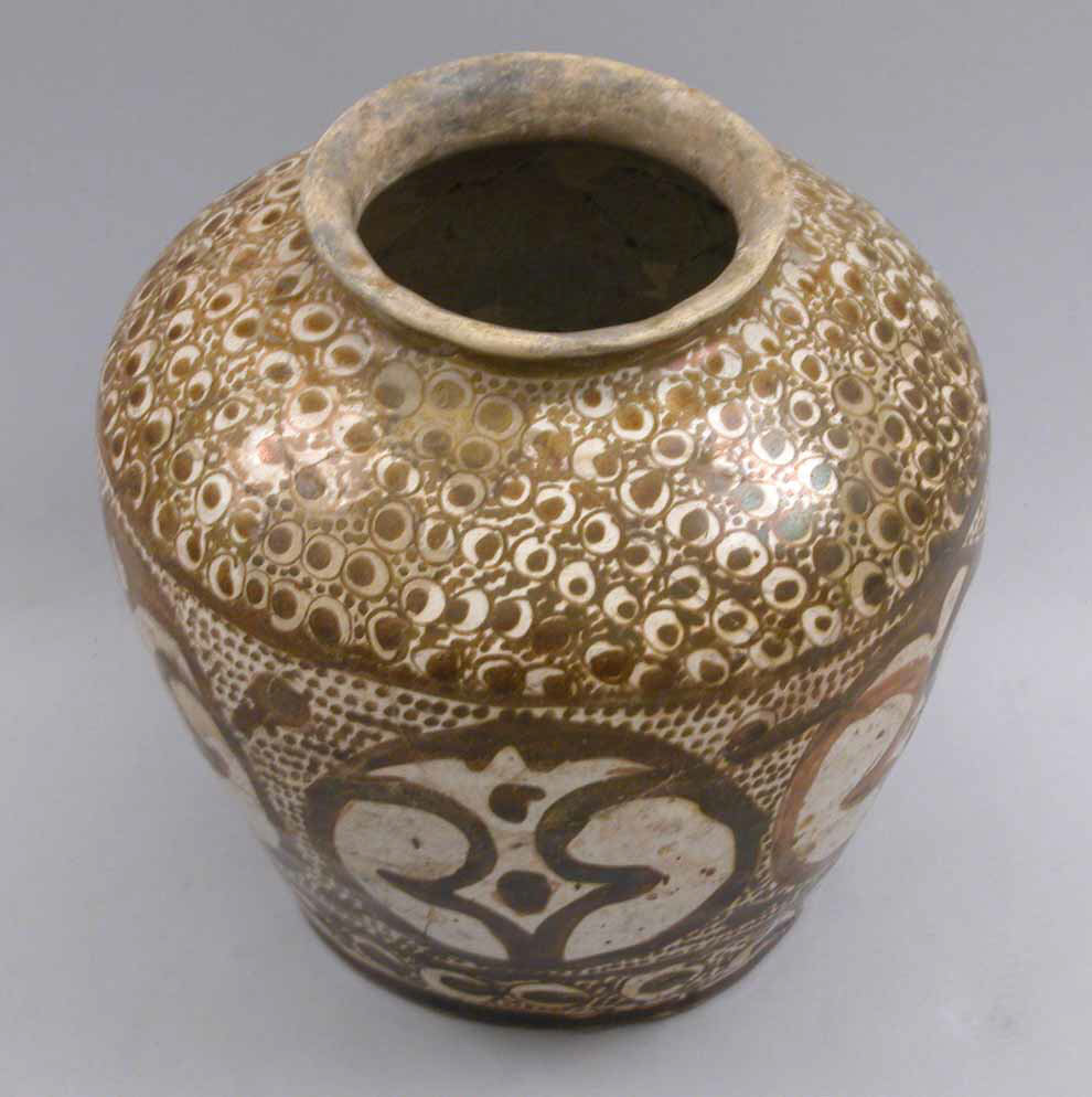 A rounded Iraqi ceramic jar seen from above, with a short rim, broad patterned medallions, and bands of small peacock-eye motifs on a pale ground.