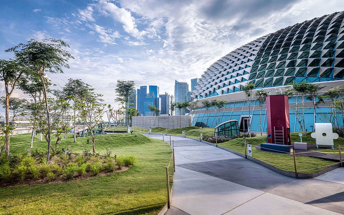 A path through Esplanade's Roof Terrace garden beside a spiked glass dome, with Singapore's office towers in the distance.