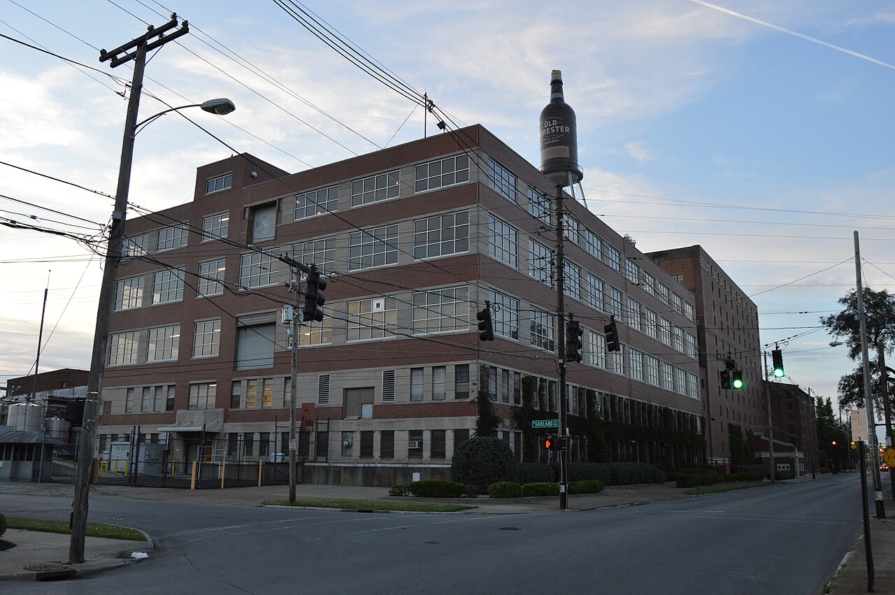 Brown-Forman 位于路易斯维尔一处路口的多层砖砌装瓶厂房与 A 号仓库，屋顶上方矗立着一只巨大的 Old Forester 酒瓶。