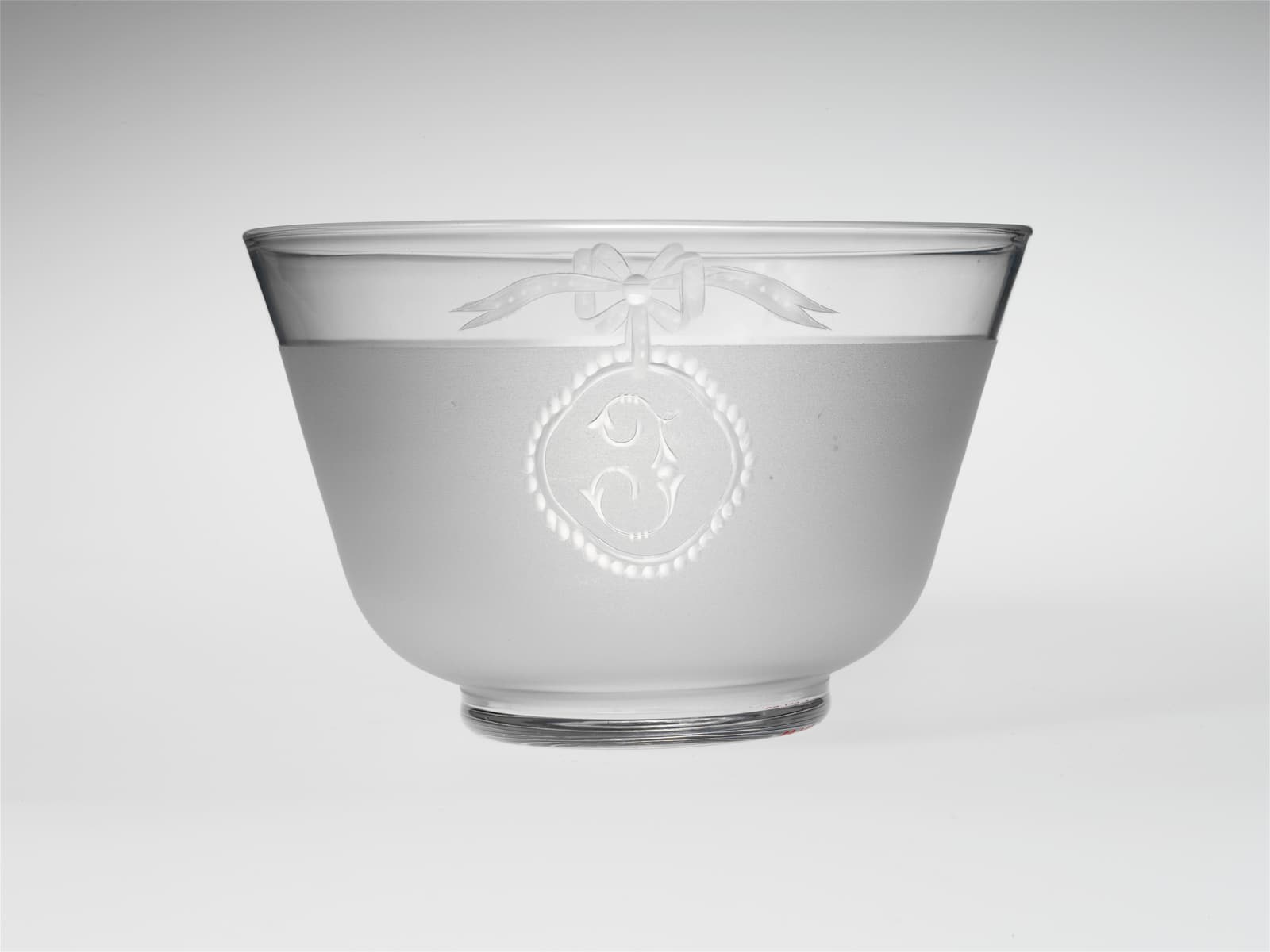A frosted clear-glass finger bowl engraved with a letter J beneath a bow motif.