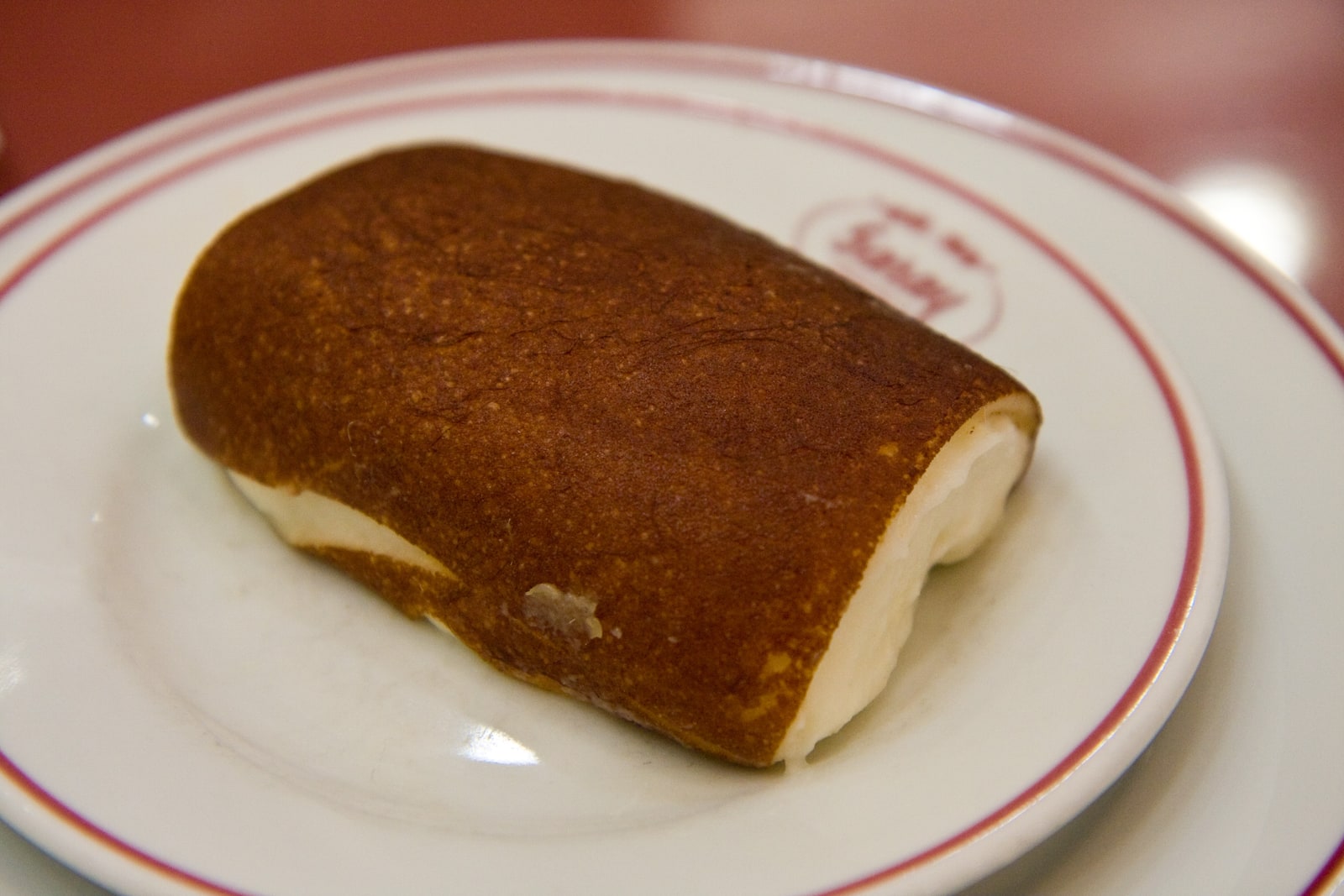 Folded kazandibi on a white plate, with a deep brown surface curving over the pale milk pudding beneath.