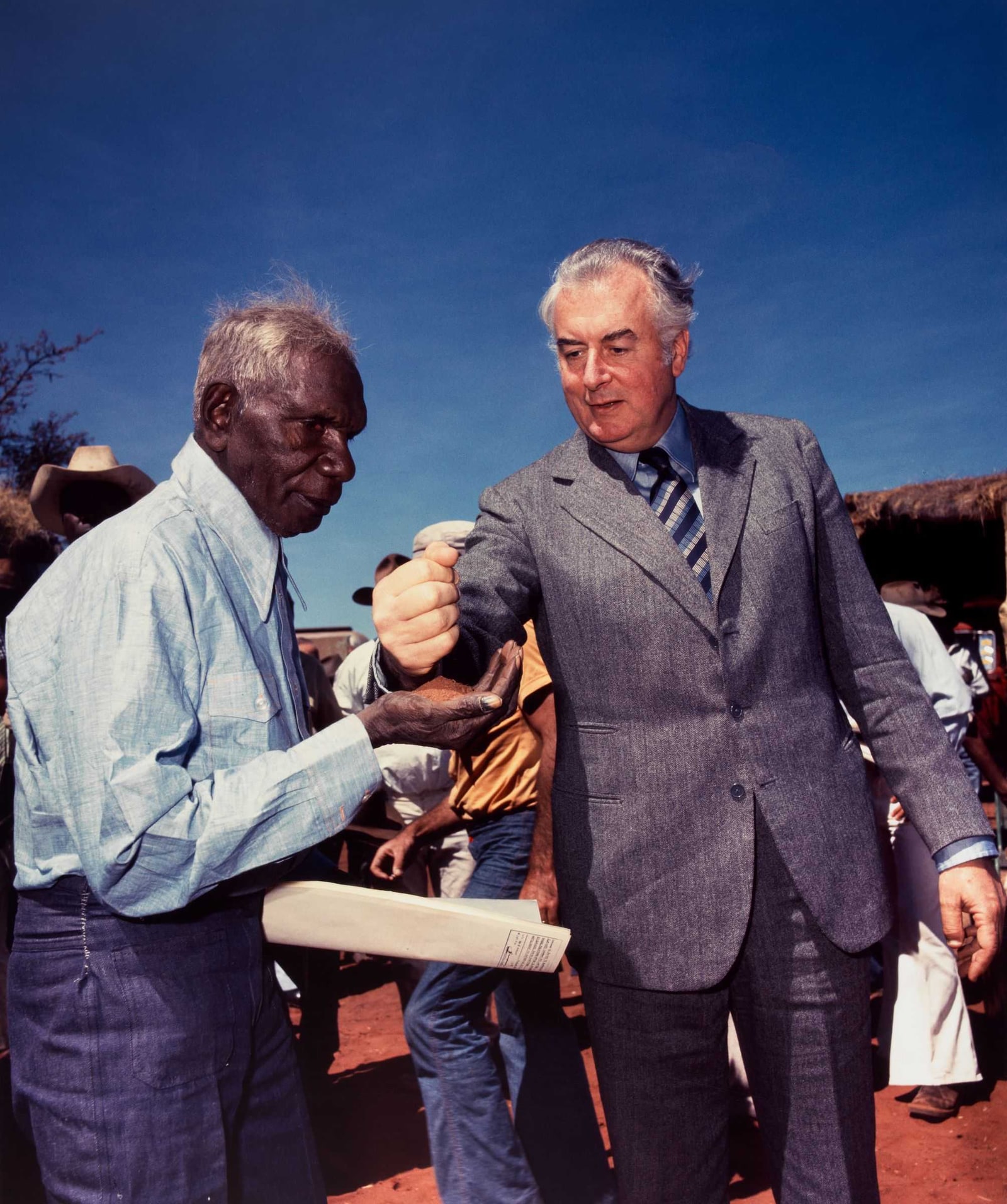 Prime Minister Gough Whitlam pours red earth into Gurindji leader Vincent Lingiari’s open hand at Daguragu in 1975 while Lingiari holds the land deeds.
