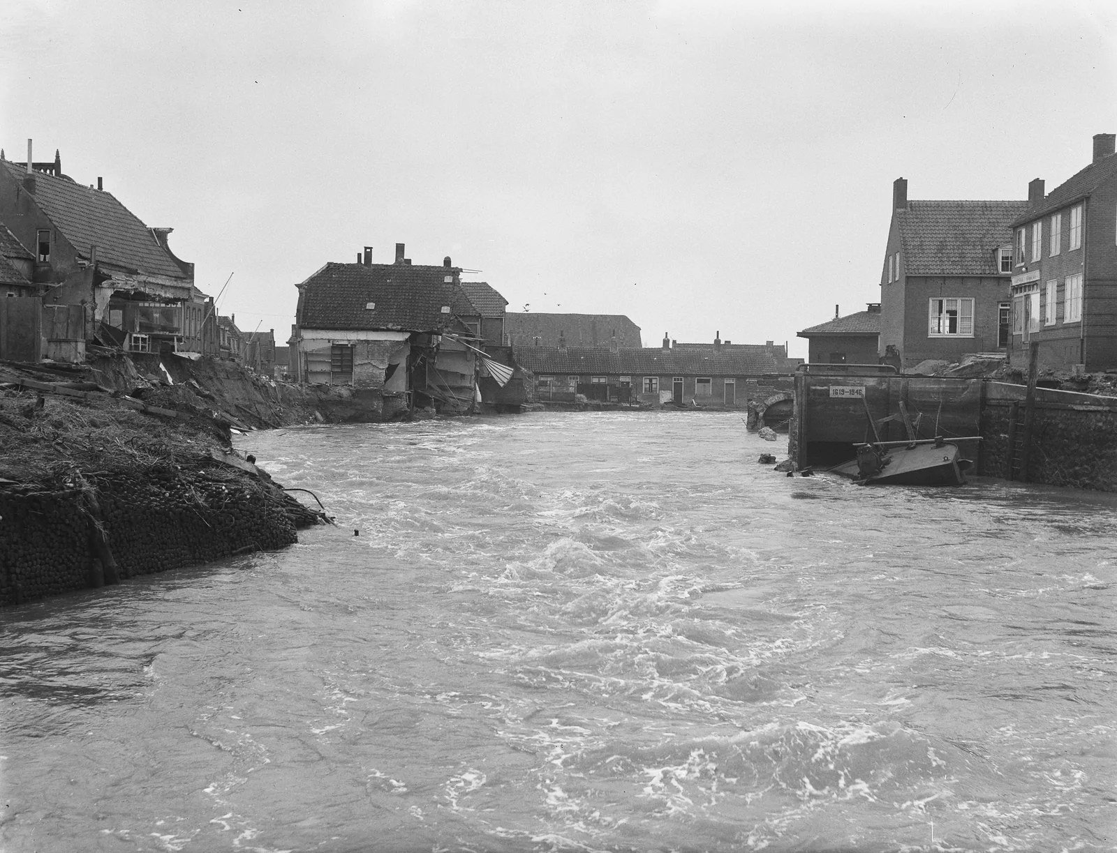 1953年北海洪灾过后，登博梅尔受损房屋之间的堤坝已经决口，洪水正从缺口奔涌而入；照片为黑白档案影像。