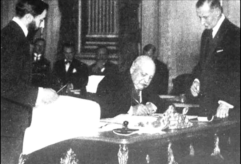 Fritz Wedel Jarlsberg signs the Svalbard Treaty at a table surrounded by formally dressed delegates.