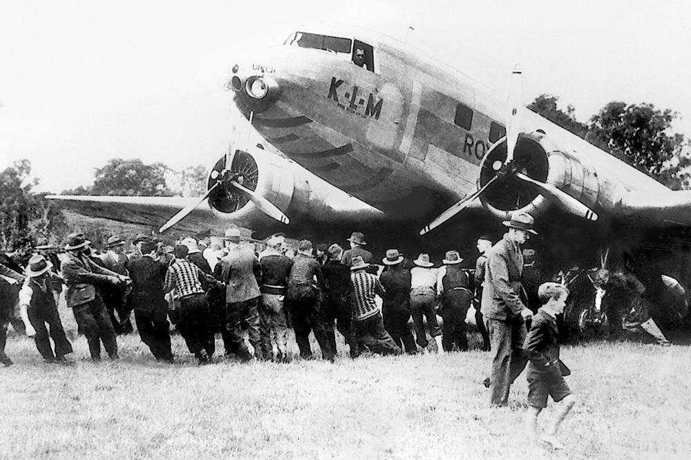 Residents lean into ropes beneath the nose and propellers of the KLM Uiver, hauling the airliner across Albury Racecourse.